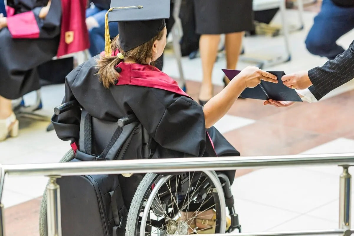 Disabled wheelchair user receives her diploma during graduation ceremony.