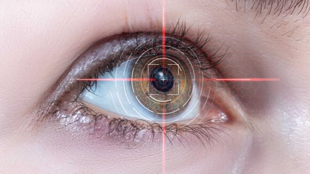 A close up picture of an eye caught in the crosshairs of a laser.