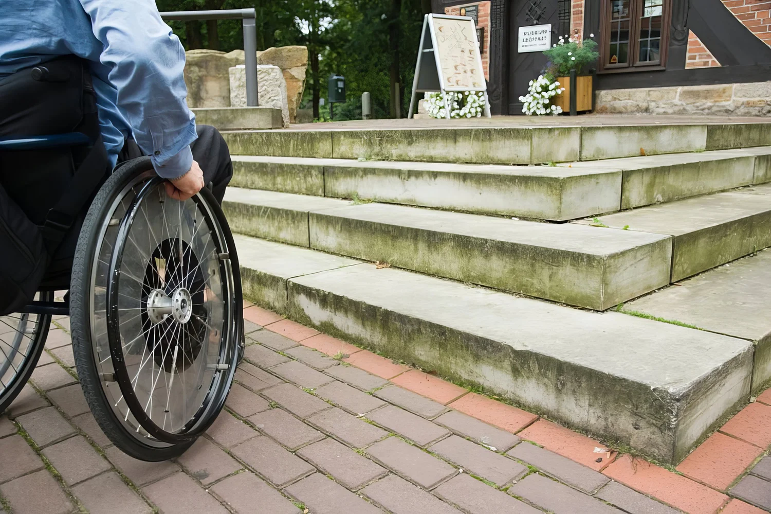 Wheelchair user in front of staircase barrier