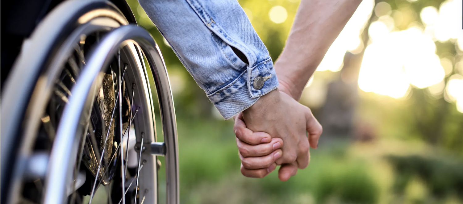 Disabled young woman and her boyfriend holding hands. Unrecognizable Caucasian people.
