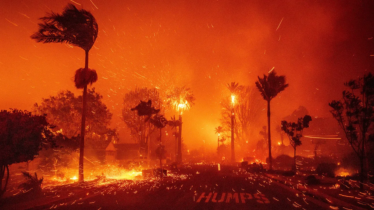 A scene of intense wildfires, with palm trees and vegetation engulfed in flames, embers scattering through the air, and a vibrant orange hue dominating the environment.